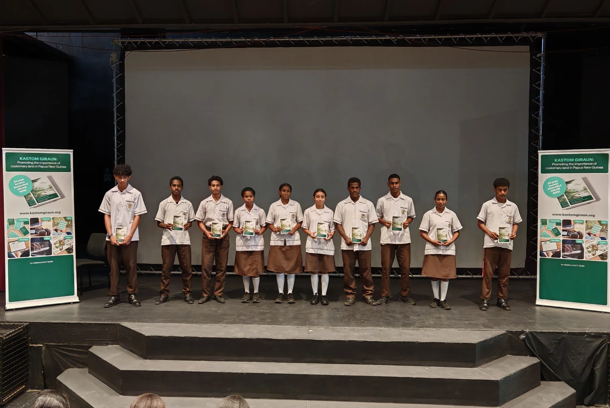 Students receiving the Kastom Giraun Booklet on stage